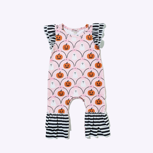 A baby romper with a light pink background featuring a repeating pattern of orange jack-o'-lanterns and black spider webs, finished with black and white striped ruffled shoulder straps and leg cuffs.